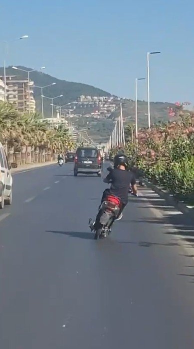 ALANYA’DA MOTOSİKLET ÜZERİNDE AYAKTA İLERLEYEN SÜRÜCÜNÜN TEHLİKELİ YOLCULUĞU KAMERADA